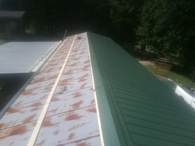Old rusted panels beside newly installed green metal roofing — Wind Damage Roof Repair by Roofing Brothers in Moorland
