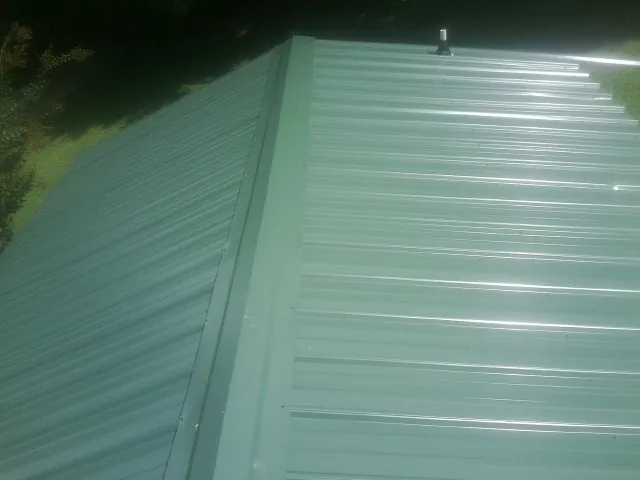 New green metal panels meeting at the ridge of a roof — Flat Roof Repair work by our crew in Moorland
