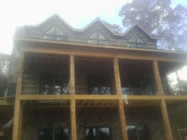 Dormers and porch framing on a large log home under construction — Roof Coating work by our crew in Moorland