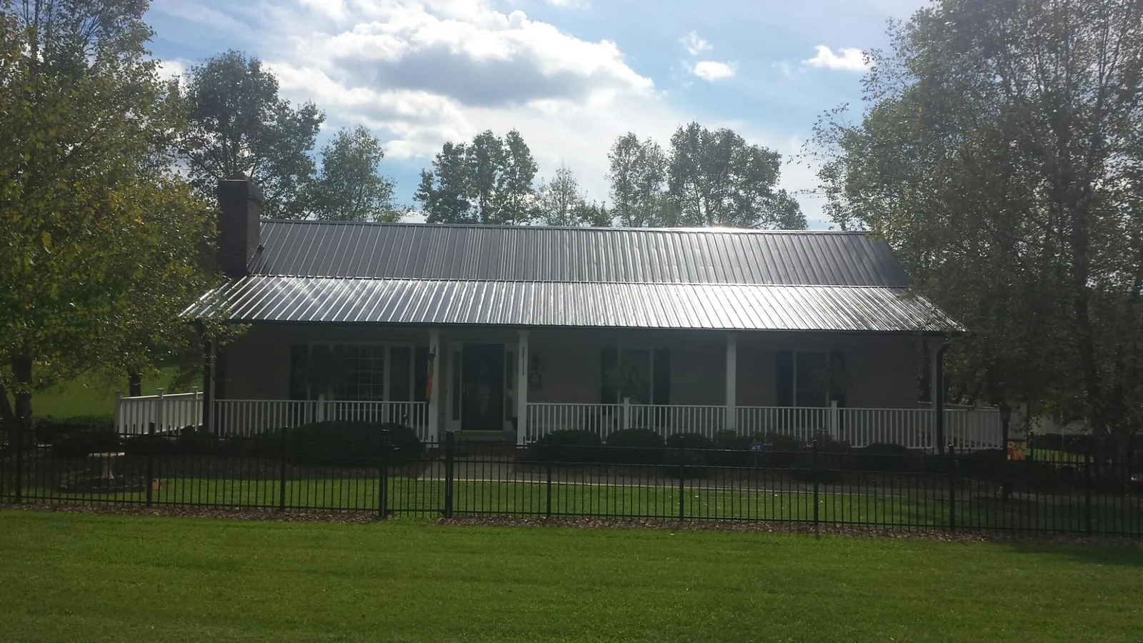 Gray metal roof on a brick ranch with a full width front porch — Gutter Guard Installation work by our crew in Moorland