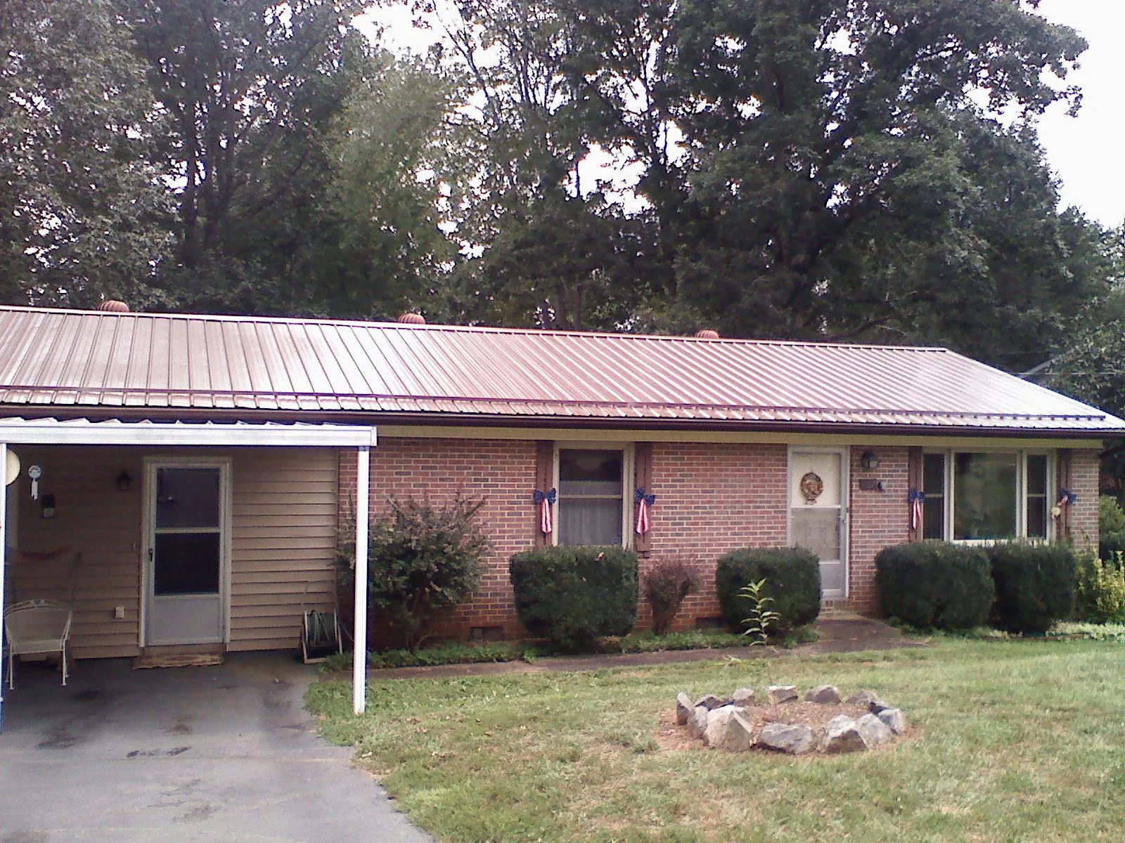 Bronze metal roof and carport on a brick ranch home — Roof Repair work by our crew in Moorland