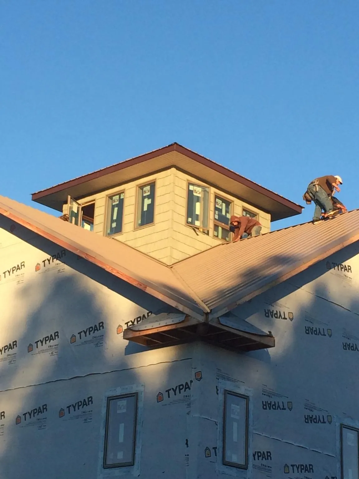 Roofers working around a rooftop cupola on a new metal roof at sunset — Roof Waterproofing in Moorland by Roofing Brothers